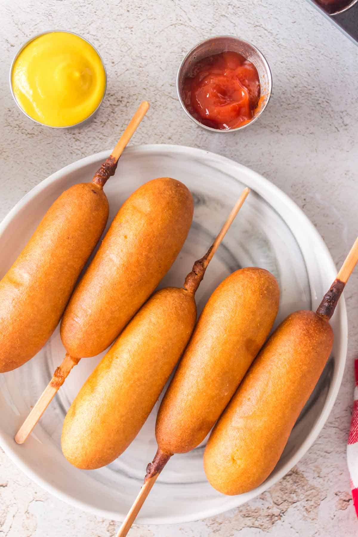 air fryer corn dogs in a row on a plate