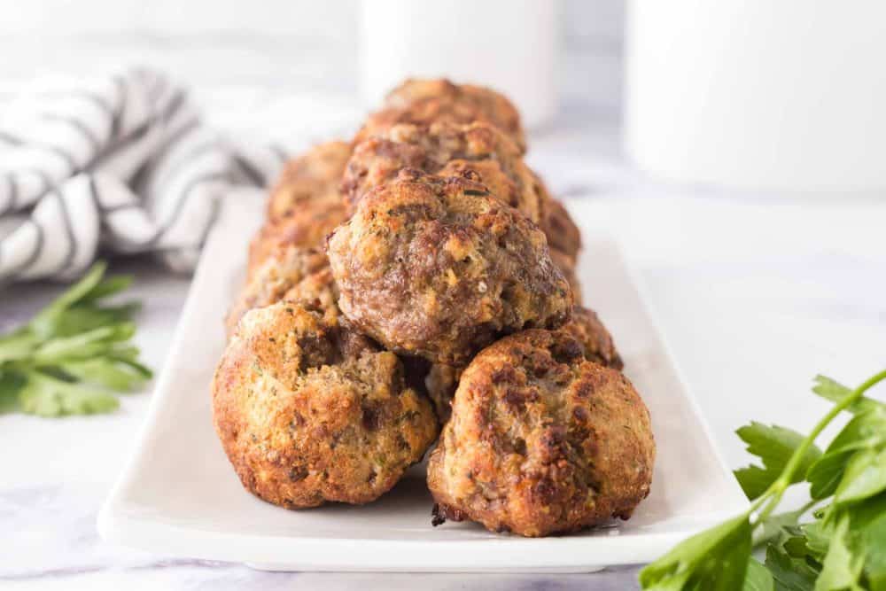 Cooked meatballs that are displayed on a white plate. 