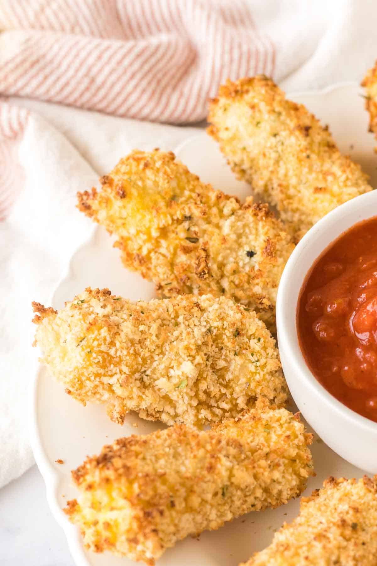 close up circular plate with a ring of air fryer mozzarella sticks around marinara sauce