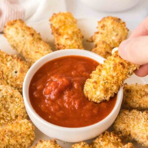 POV dipping air fryer mozzarella sticks in marinara sauce