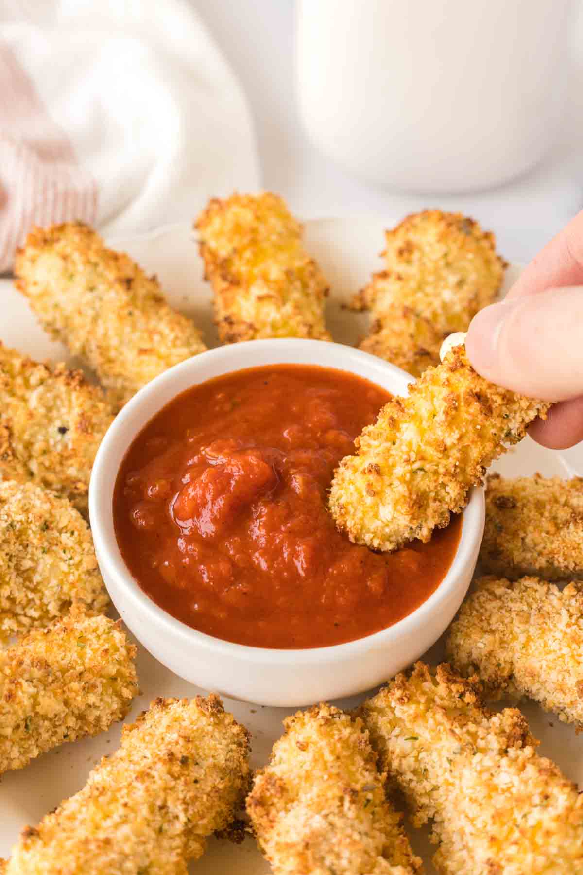 POV dipping air fryer mozzarella sticks in marinara sauce