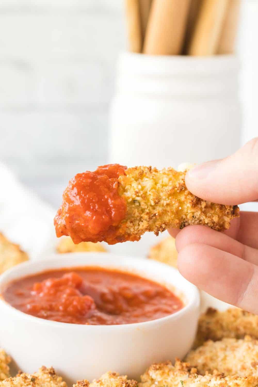 POV dipping air fryer mozzarella sticks in marinara sauce