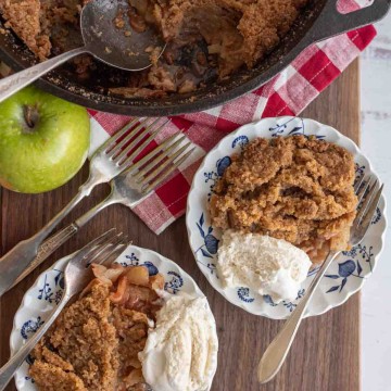 apple crumble served on plates with ice cream and the whole crumble in a cast iron pan