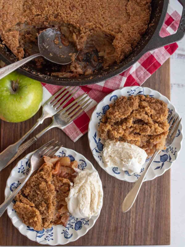 apple crumble served on plates with ice cream and the whole crumble in a cast iron pan