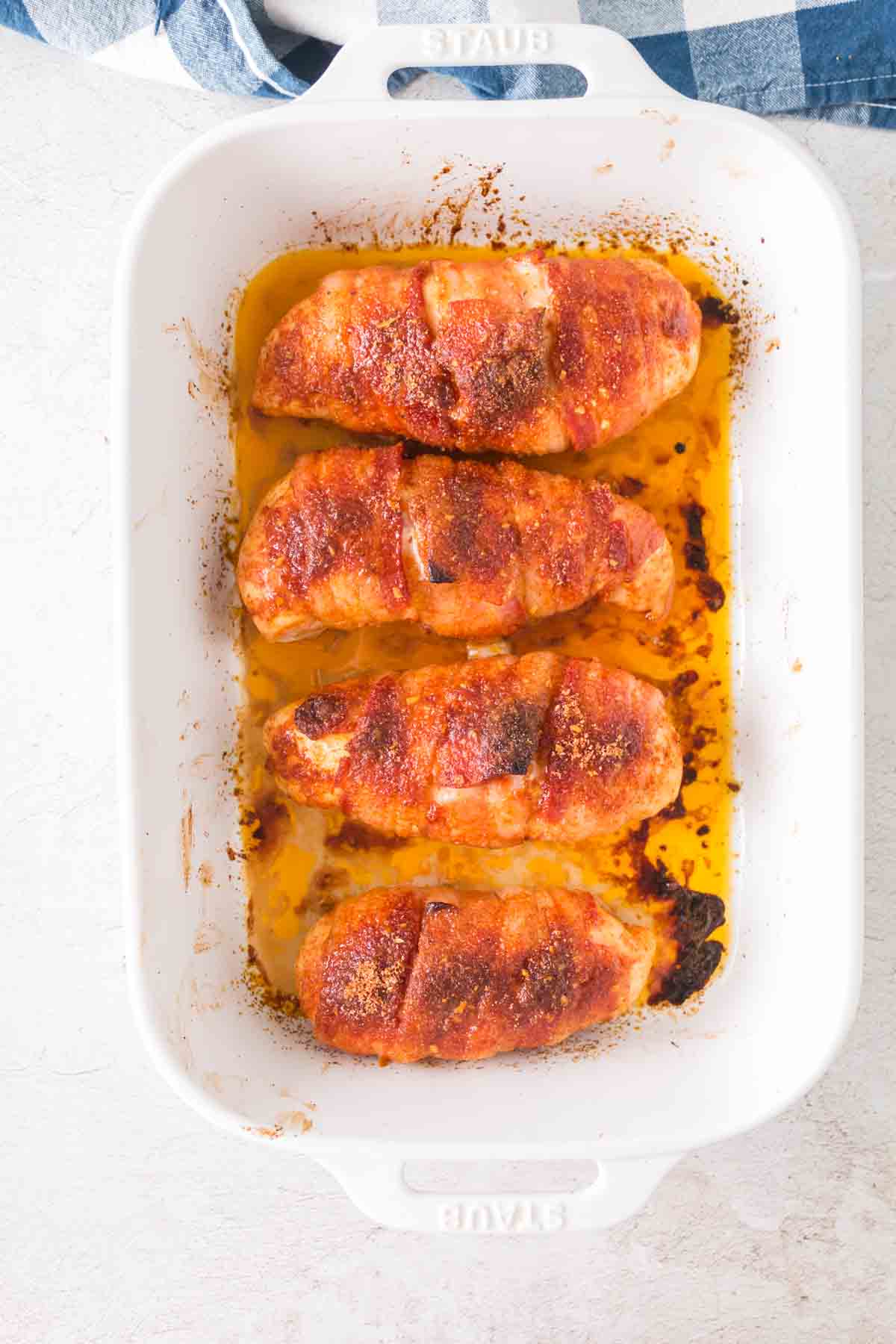Bacon wrapped chicken in a baking dish.