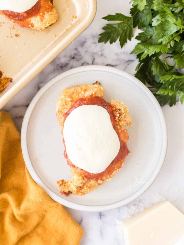 Baked chicken parmesan on a white plate top view