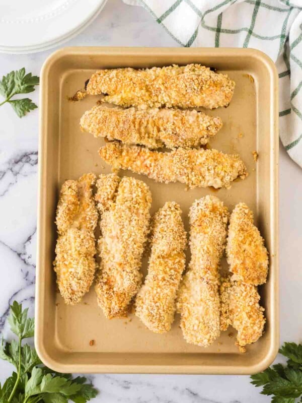 breaded chicken tenders on a baking sheet