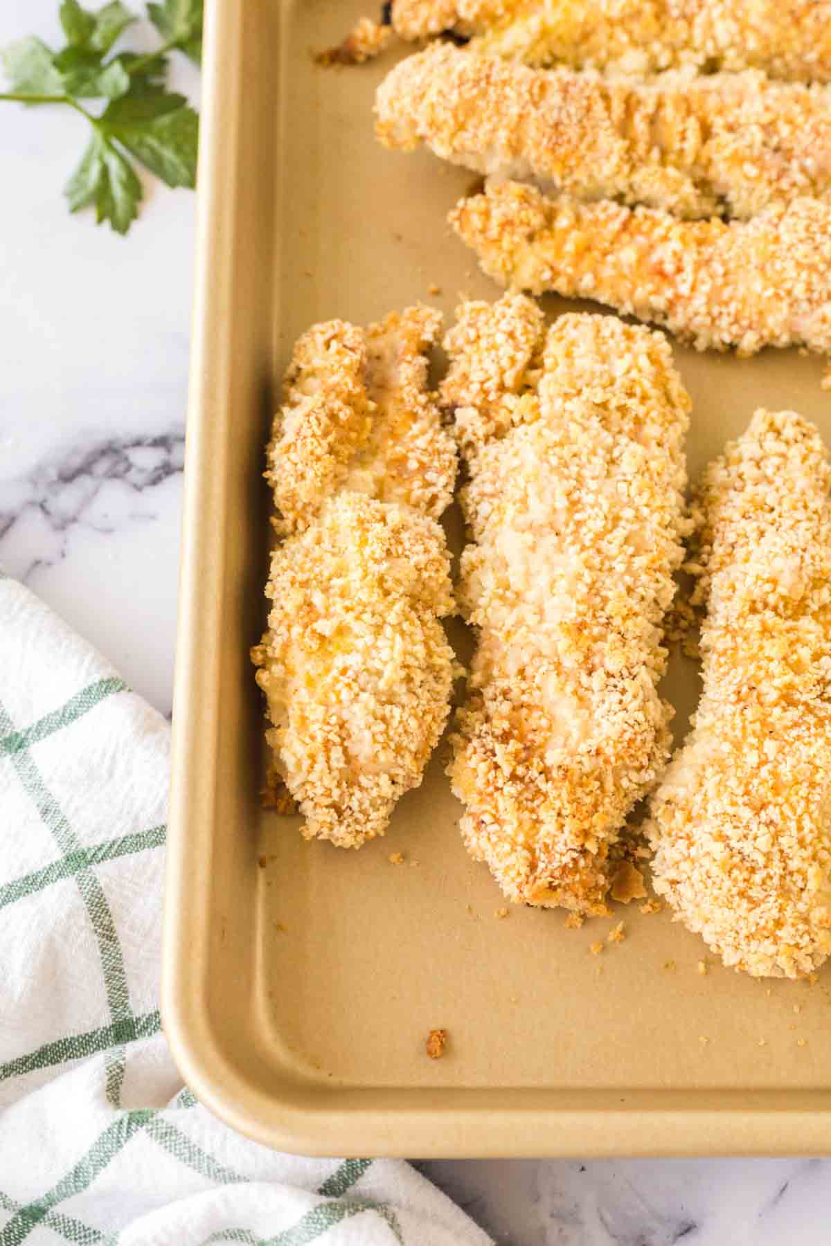 Baked chicken tenders on a baking sheet.