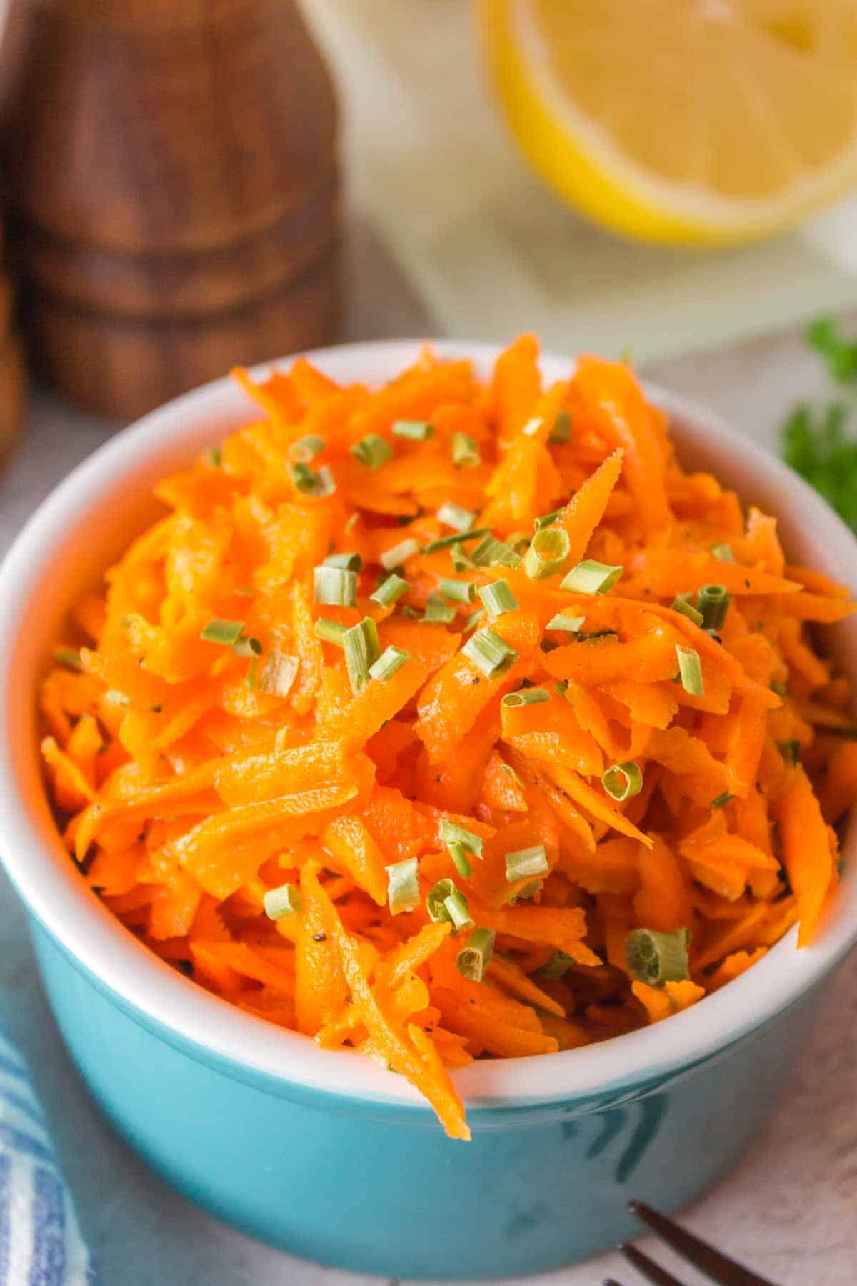 shredded carrot salad in a small blue bowl