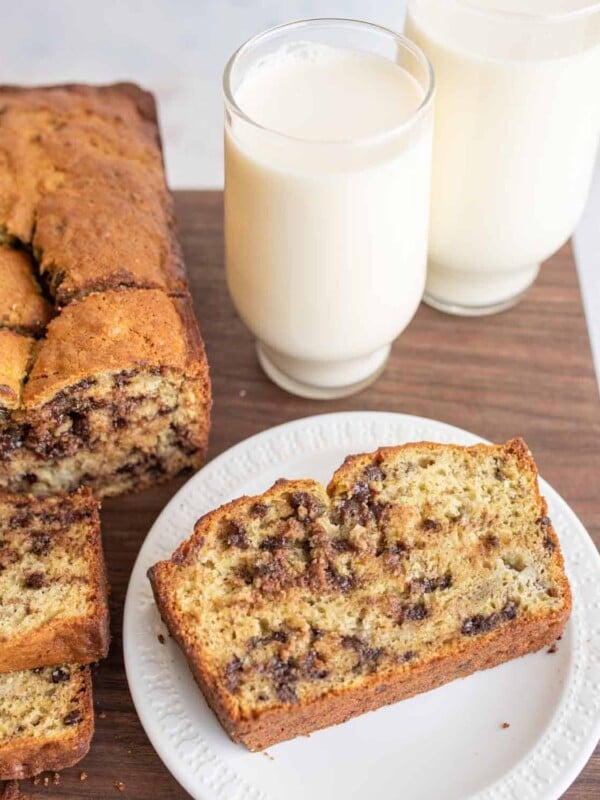 chocolate chip banana bread loaf sliced and plated next to a glass of milk