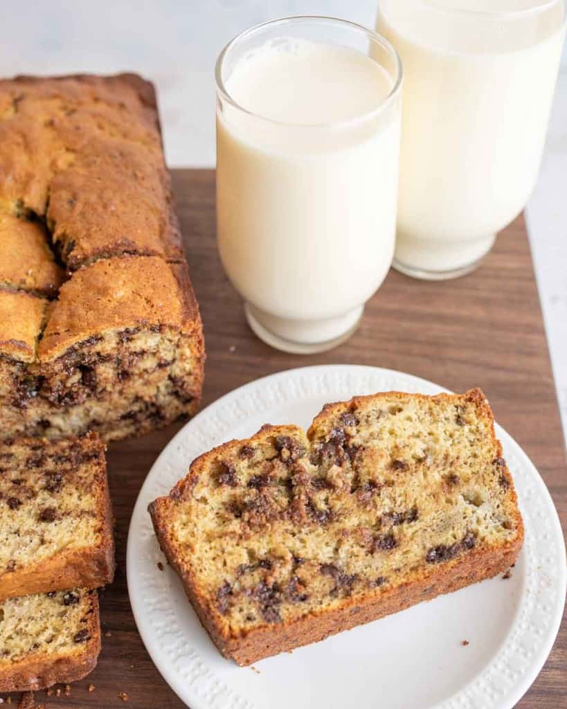 chocolate chip banana bread loaf sliced and plated next to a glass of milk
