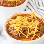Cincinnati chili served into small white dishes with shredded cheese on top