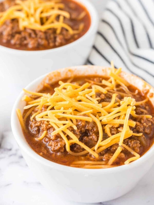 Cincinnati chili served into small white dishes with shredded cheese on top