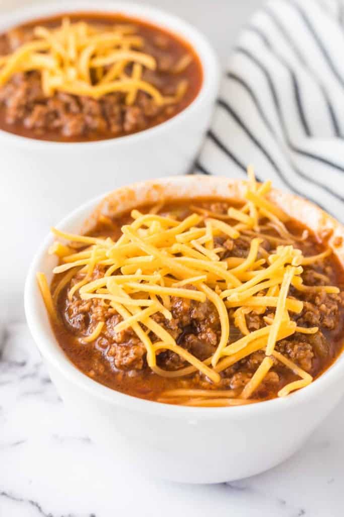 Cincinnati chili served into small white dishes with shredded cheese on top