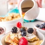 french toast bake with a serving dished onto a plate with powdered sugar berries and syrup