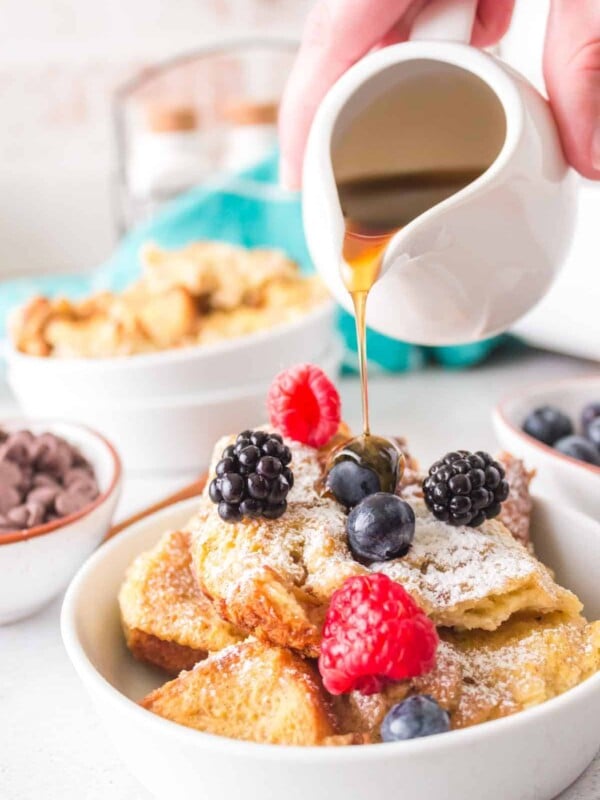 french toast bake with a serving dished onto a plate with powdered sugar berries and syrup