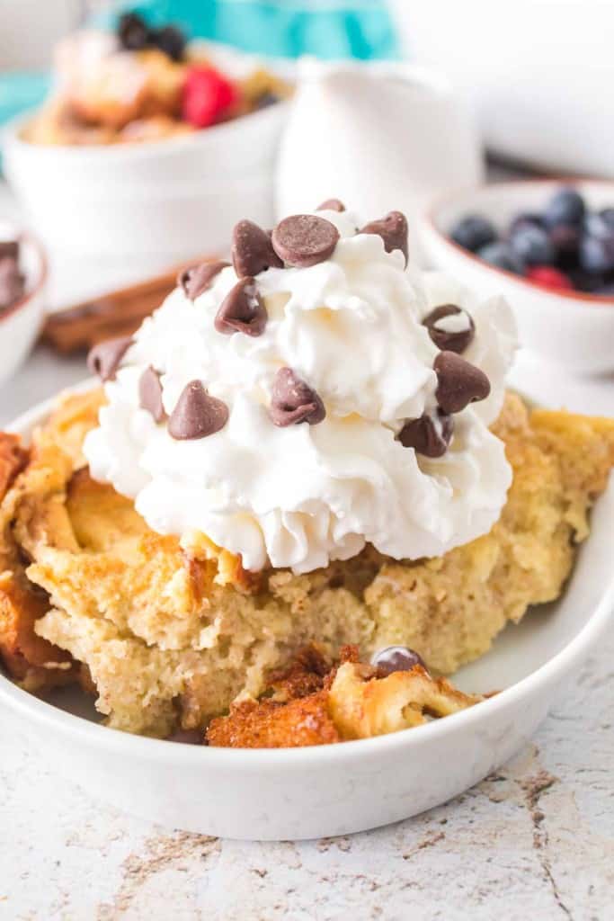 french toast bake with a serving dished onto a plate with whipped cream and chocolate chips on top