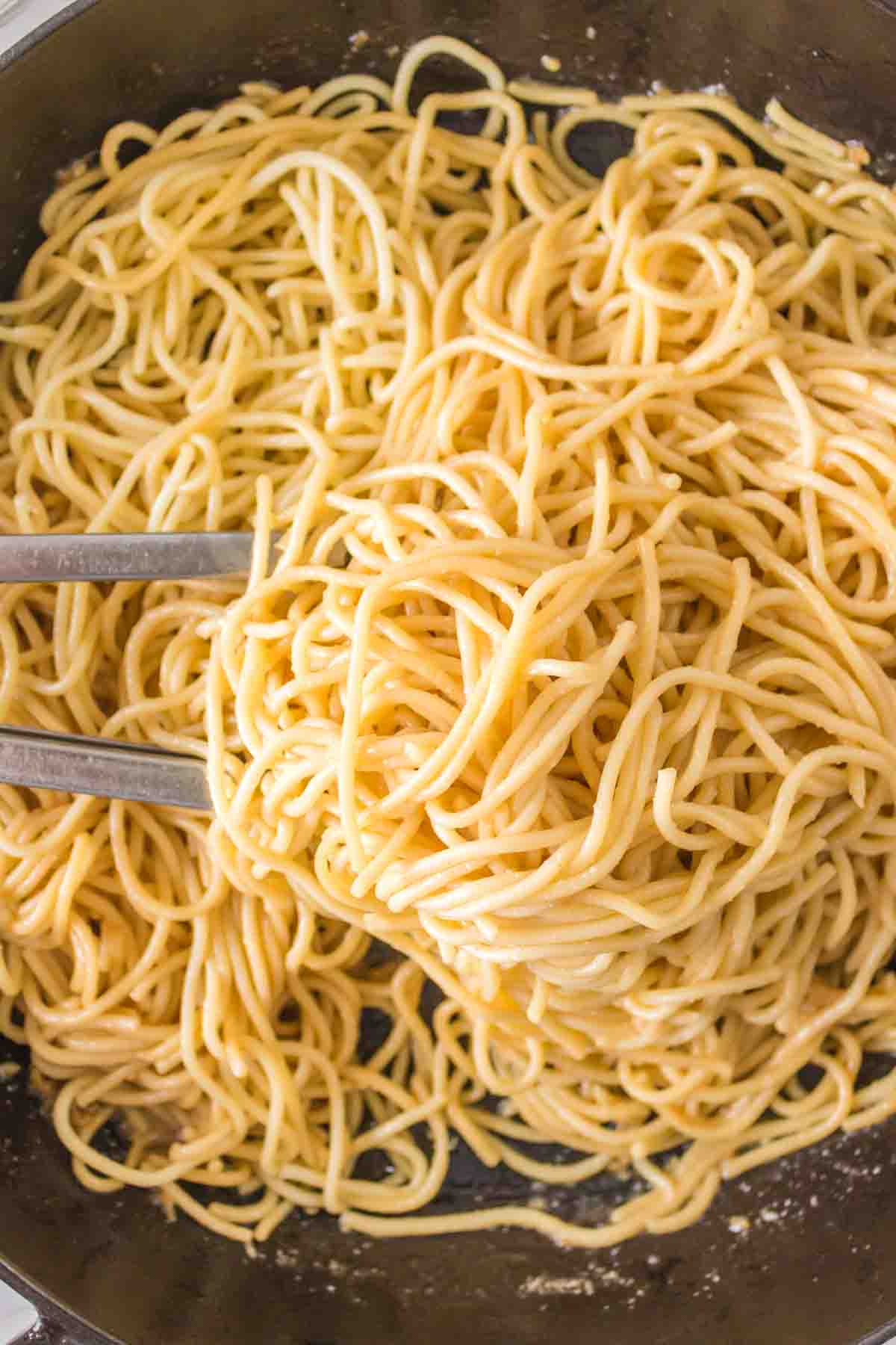 pan of garlic noodles and tongs