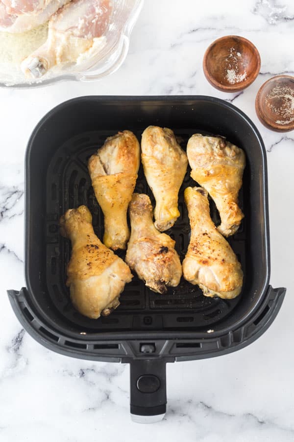 pale gold chicken drumsticks in the air fryer basket