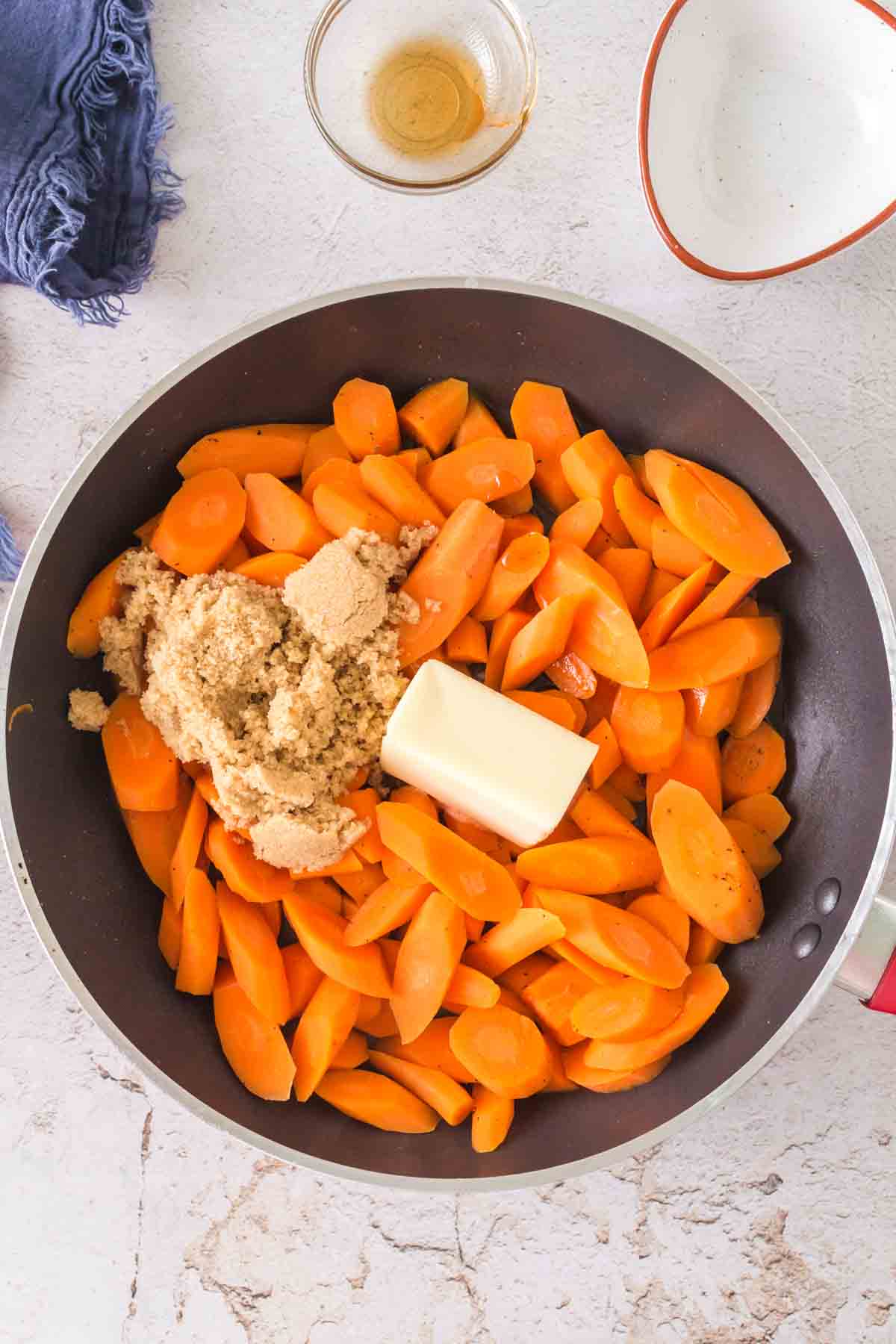 raw carrots with brown sugar and butter in a pan to begin to glaze the carrots