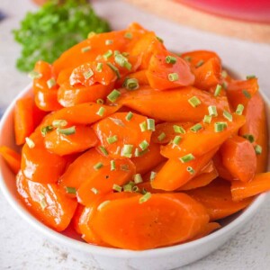 glazed carrots in a white dish with chives on top