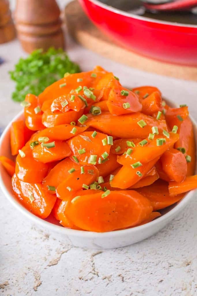 glazed carrots in a white dish with chives on top