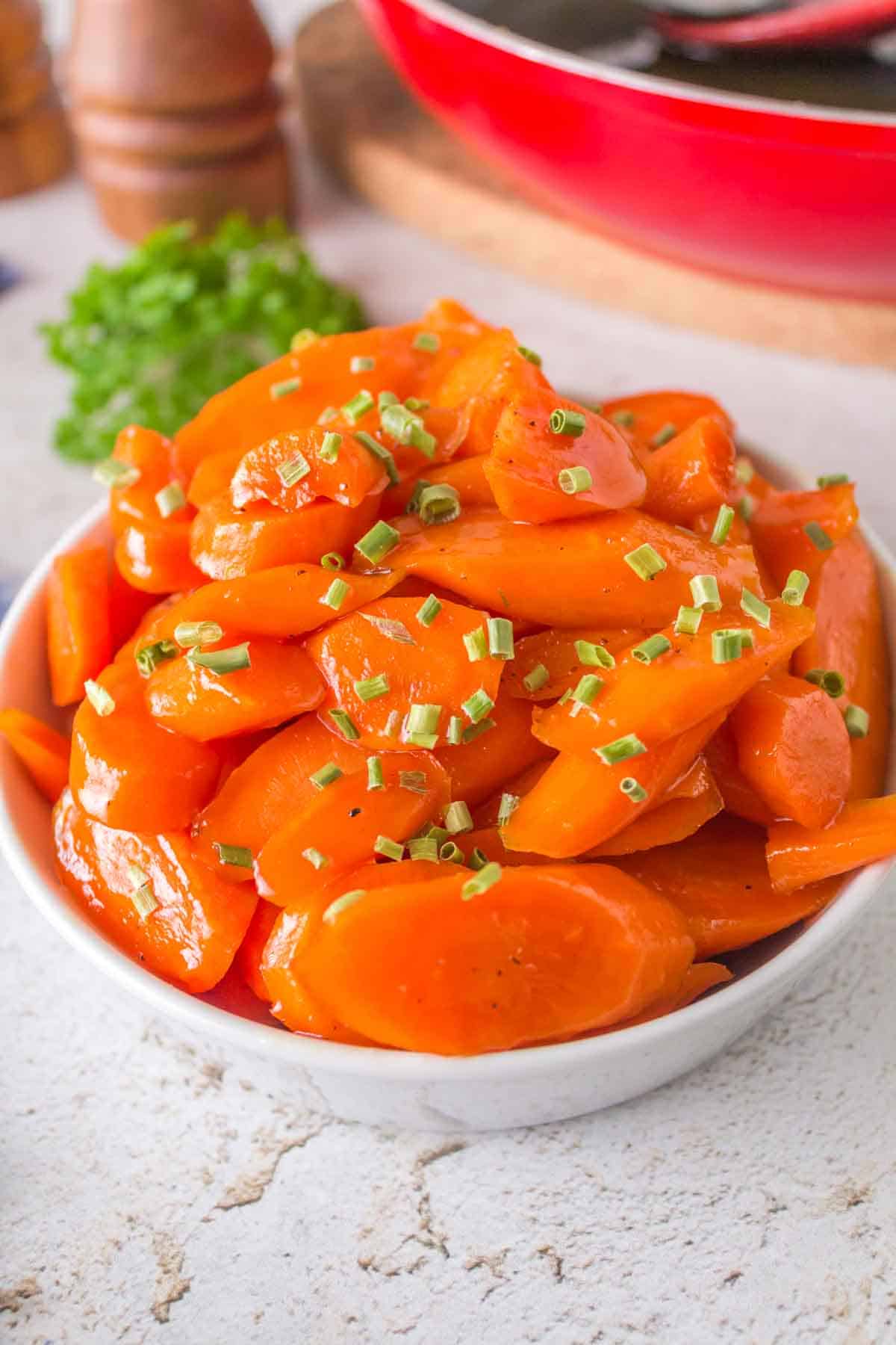 glazed carrots in a white dish with chives on top
