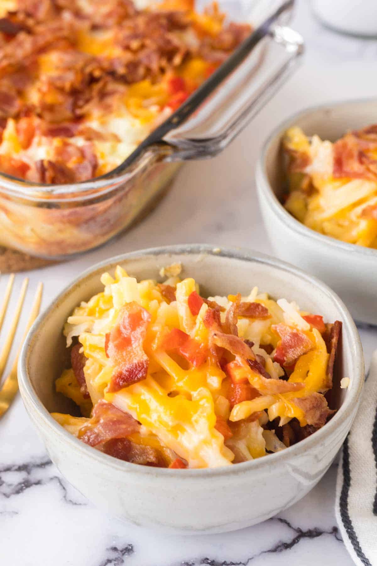 small portion dishes of the baked hash brown breakfast casserole with melted cheese and bacon on top