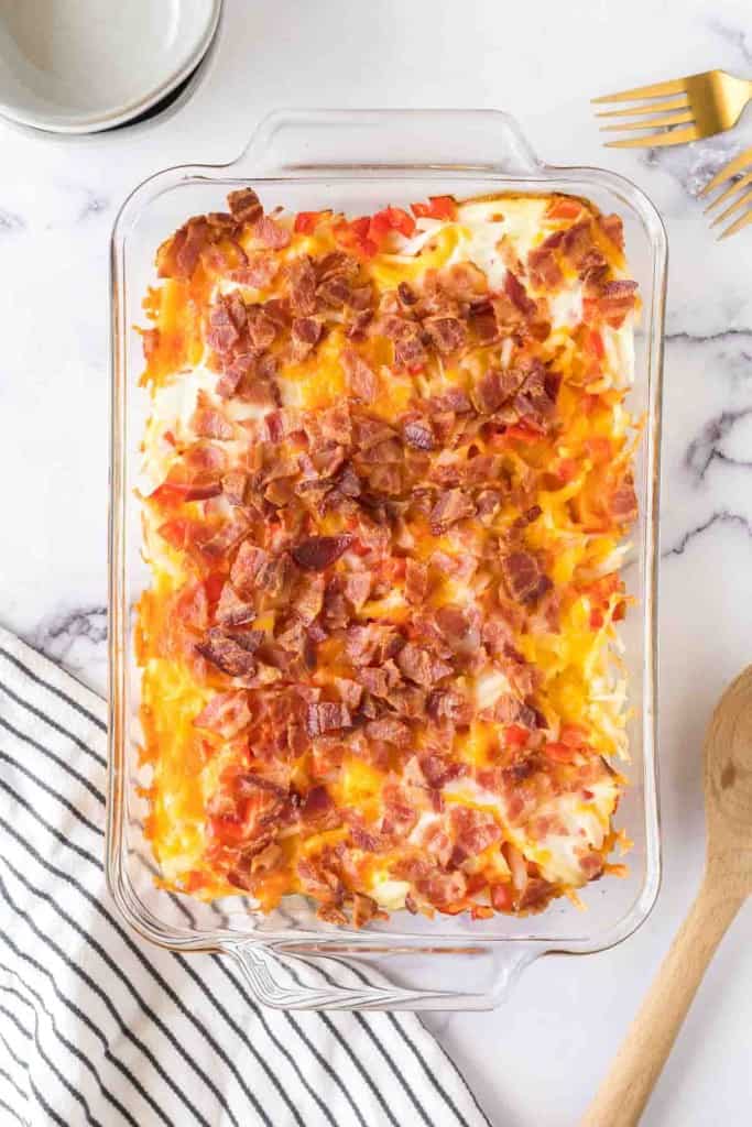 baked in a clear rectangle baking dish, hash brown breakfast casserole with melted cheese and bacon on top