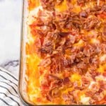 baked in a clear rectangle baking dish, hash brown breakfast casserole with melted cheese and bacon on top