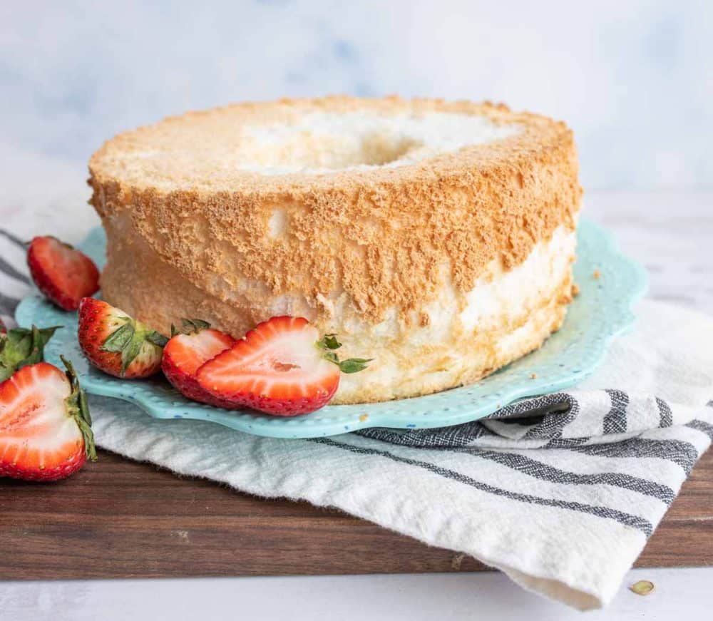 ring of fluffy homemade angel food cake with strawberries on the side