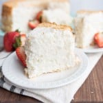 fluffy white angel food cake slice with strawberries on the side