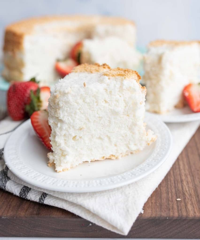 fluffy white angel food cake slice with strawberries on the side
