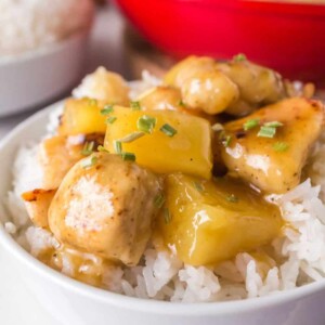 pineapple chicken served on a plate over a bed of rice