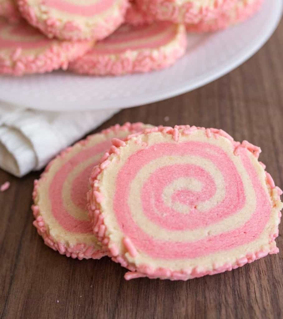 close up of pink and tan swirl decorated pinwheel cookies with pink sprinkles