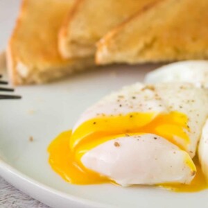 fork cutting a poached egg and its yolk gooing out