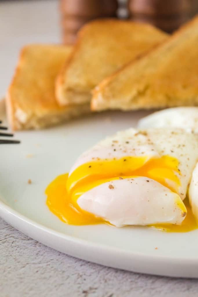 fork cutting a poached egg and its yolk gooing out
