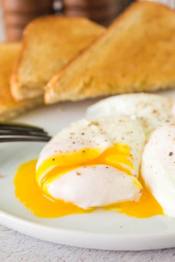 gooey poached egg on a plate and its yolk pouring out