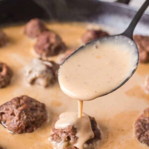 swedish meatball sauce poured over meatballs in cast iron pan