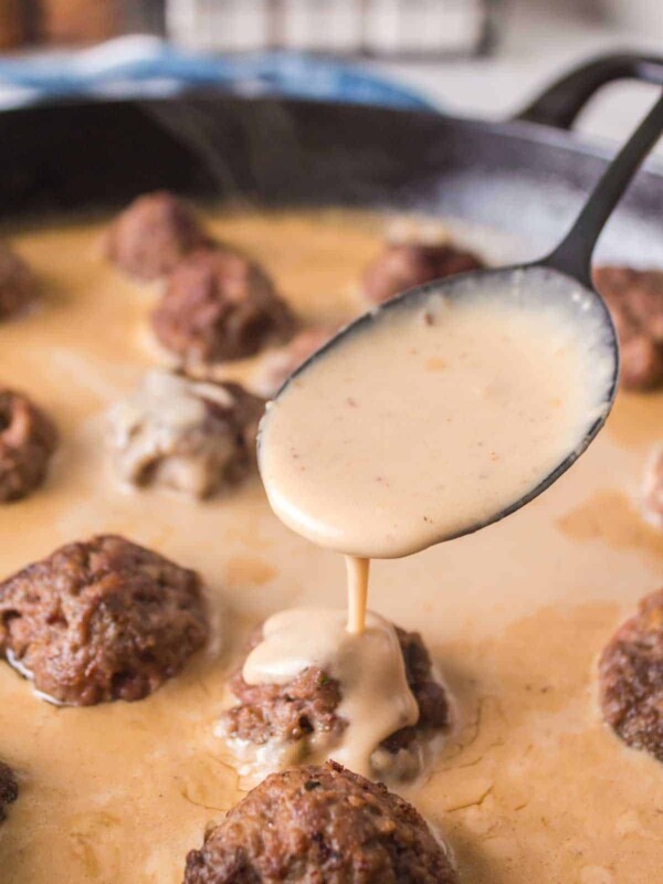 swedish meatball sauce poured over meatballs in cast iron pan