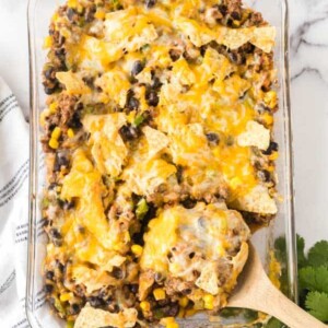 top view of a wooden spoon POV holding a baked portion of taco casserole