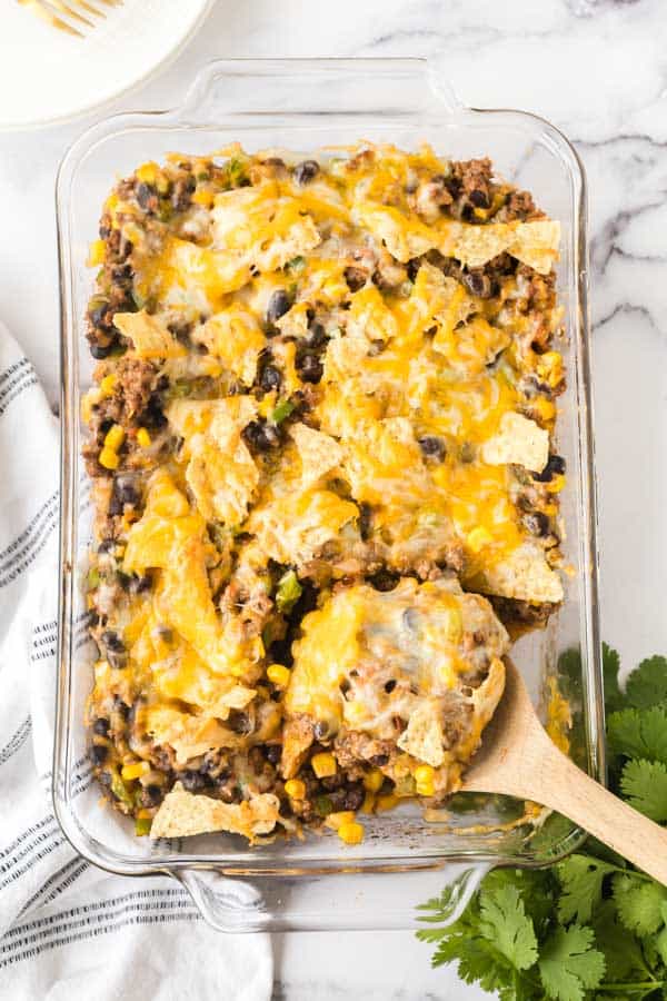 top view of a wooden spoon POV holding a baked portion of taco casserole