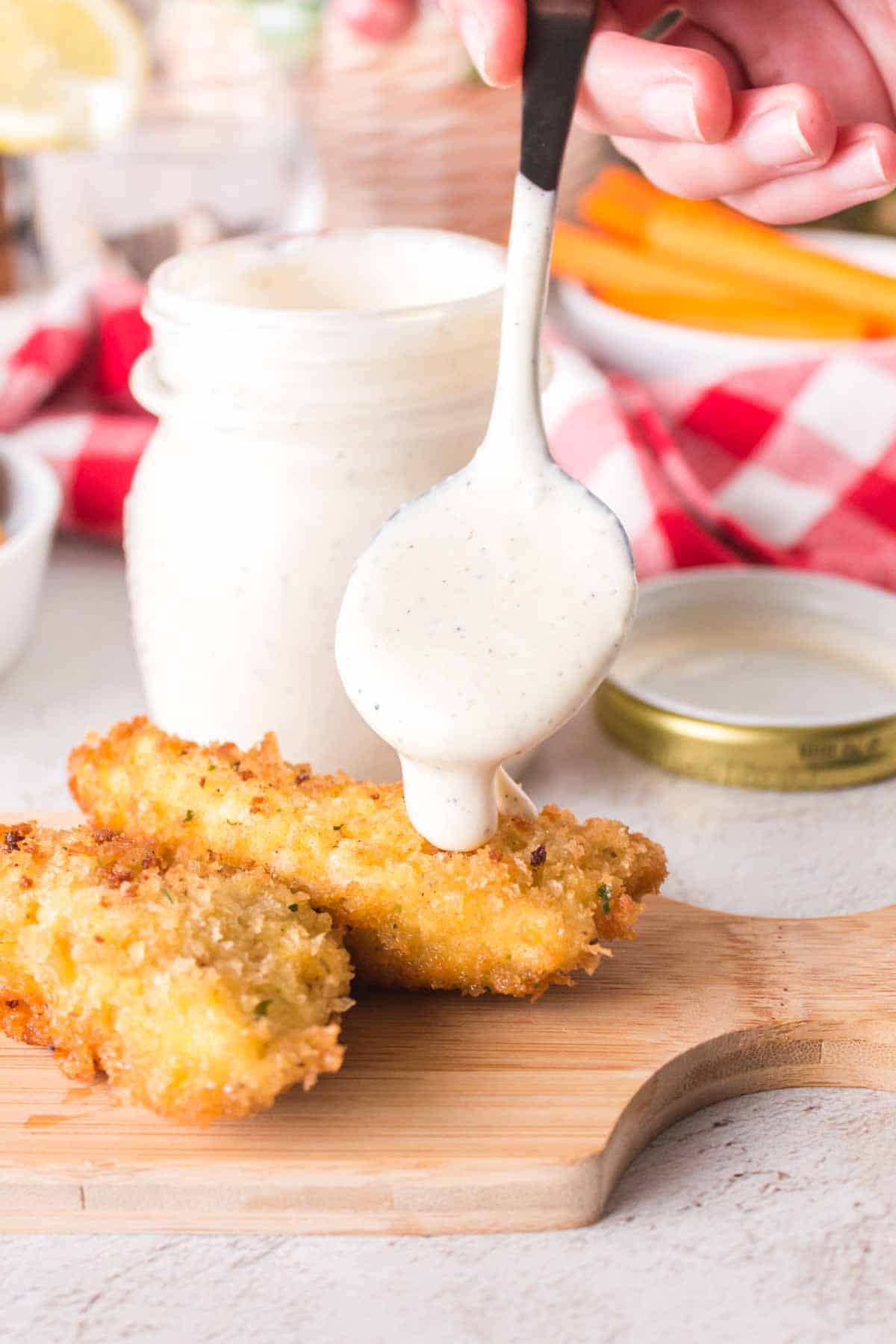 White BBQ sauce getting dripped on chicken tender.