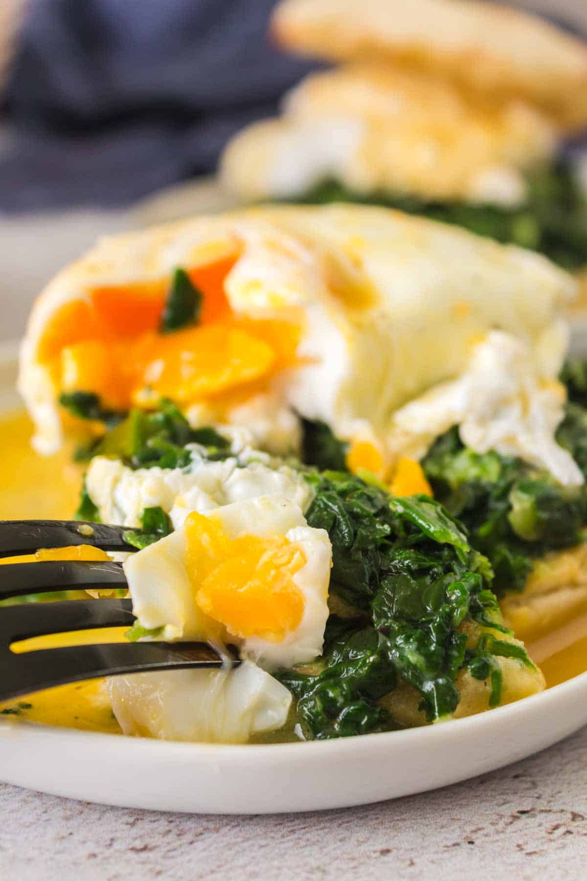 close up of eggs Florentine sliced in half on a fork