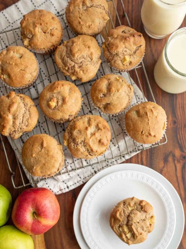 apple cinnamon muffins on a cooling rack and on a plate.