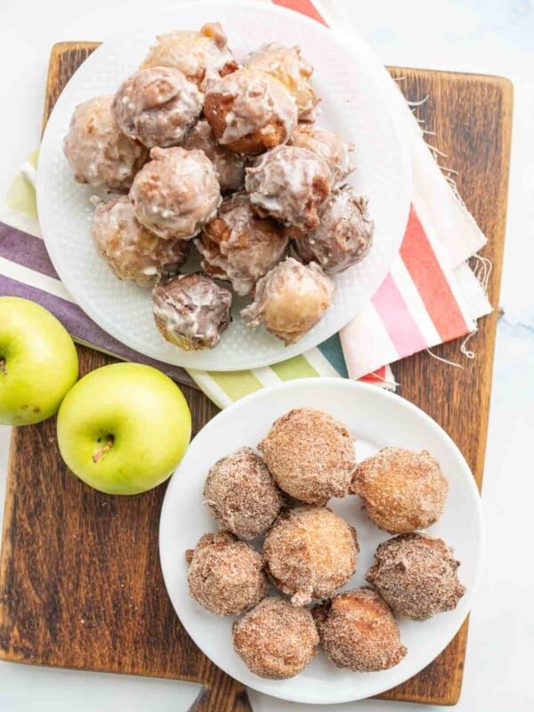 small round apple fritter bites stacked onto a plate top view