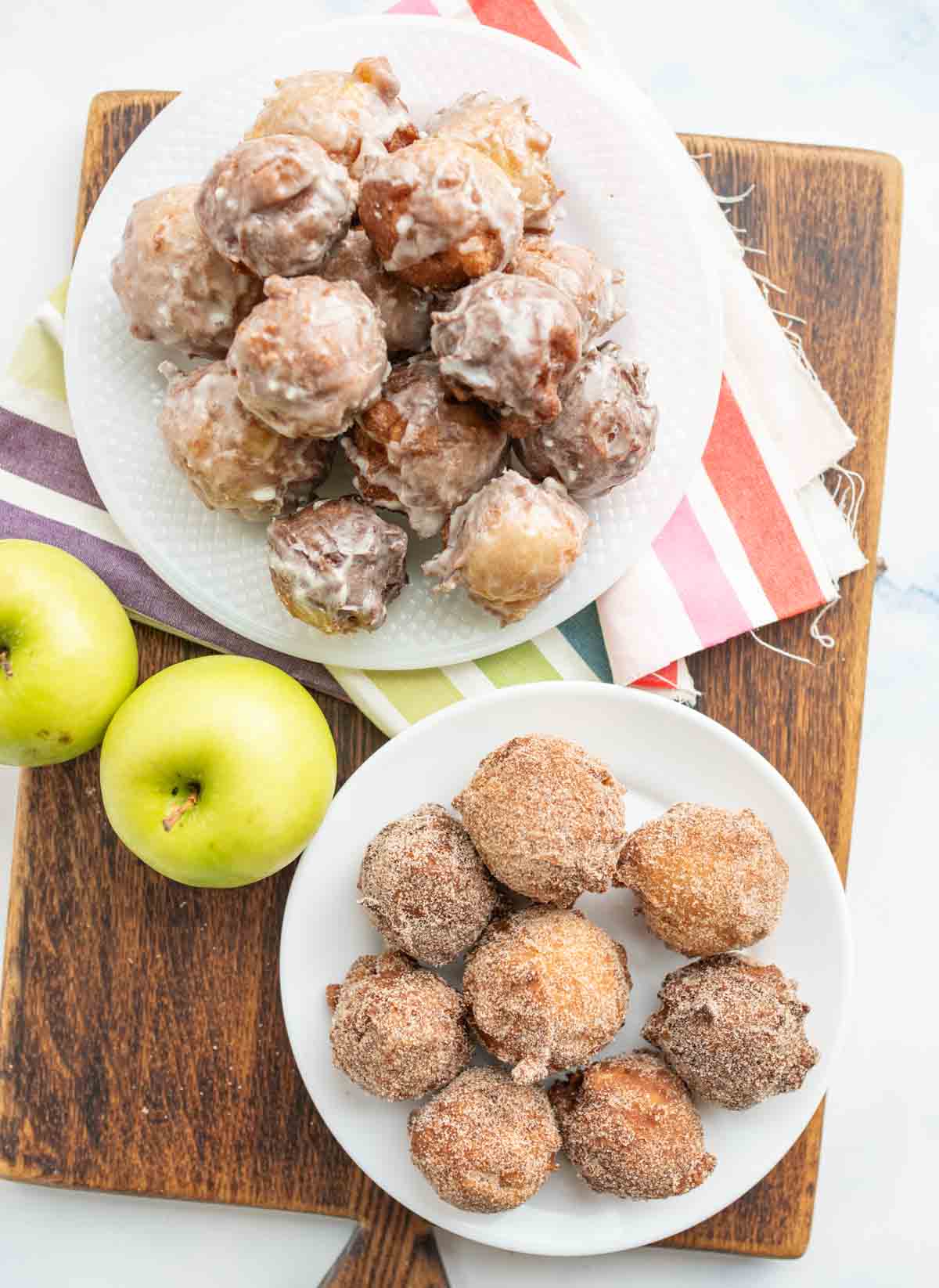 small round apple fritter bites stacked onto a plate top view
