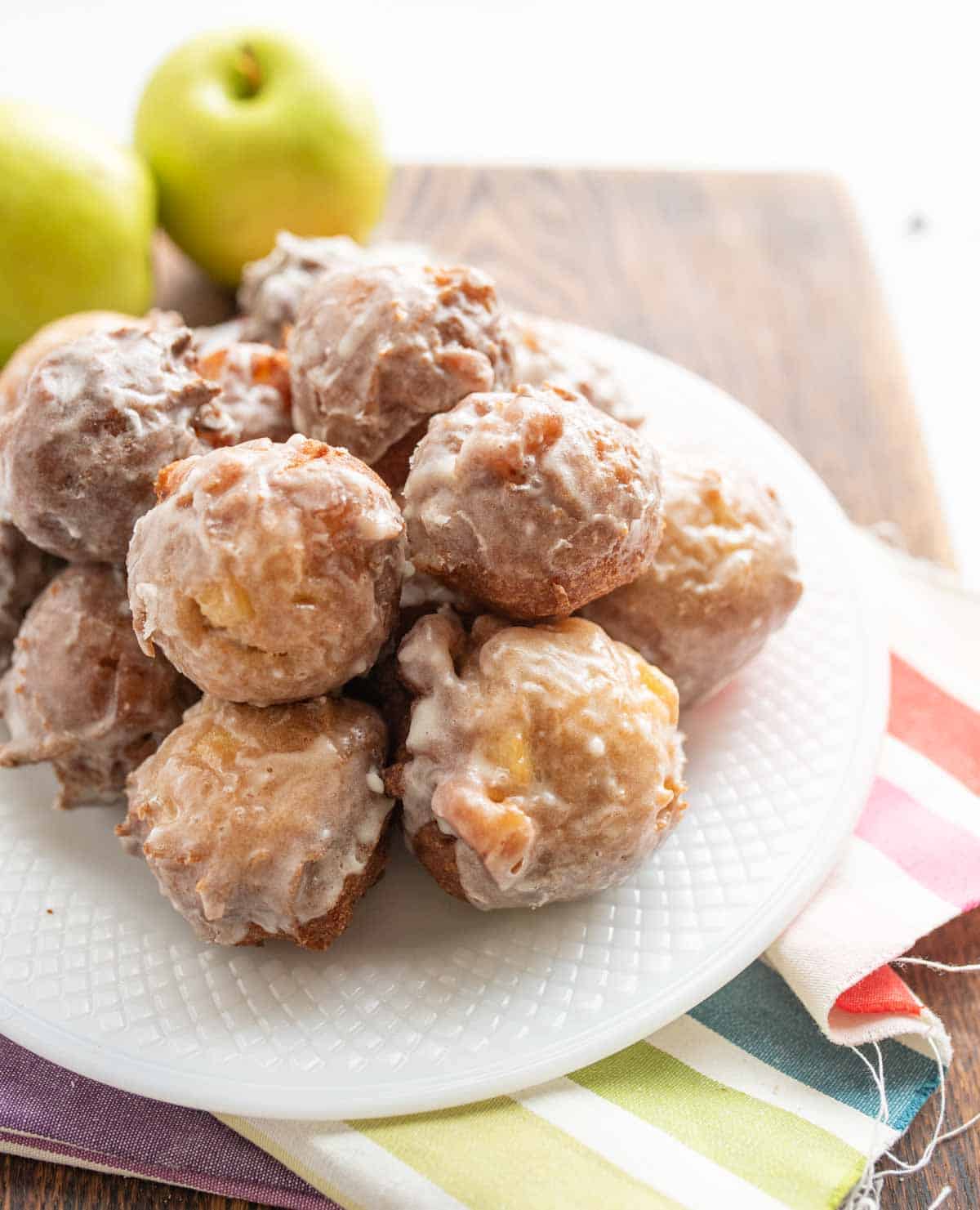 small round apple fritter bites stacked onto a plate