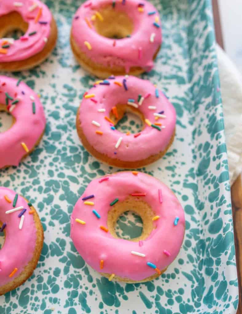 pink iced circle donuts with rainbow sprinkles