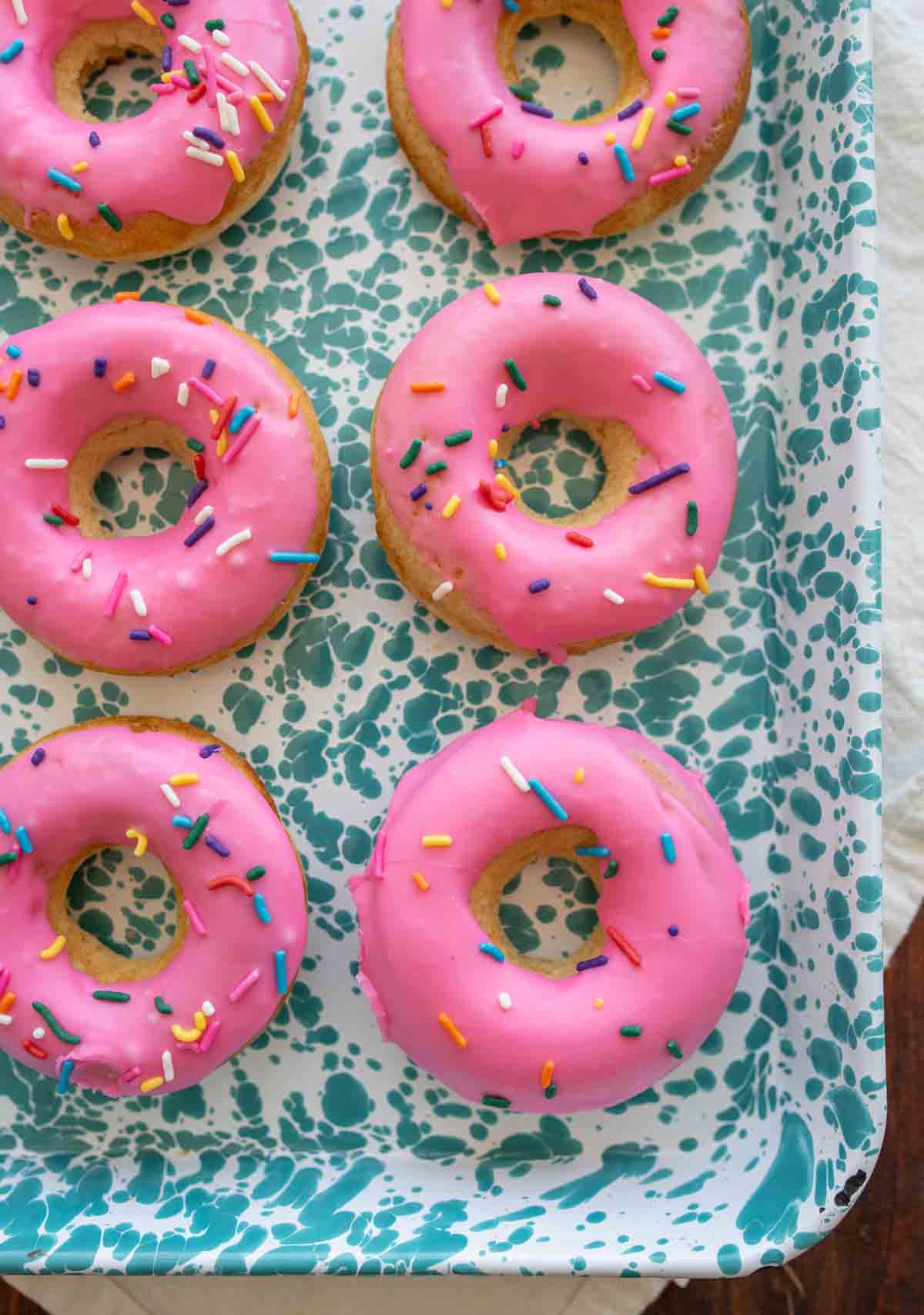 pink iced circle donuts with rainbow sprinkles